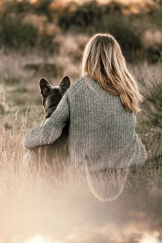 a woman sitting in the grass with her dog