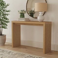 a wooden table sitting next to a plant and a mirror on top of a wall