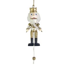 a nutcracker ornament hanging from a gold colored pole with a white background