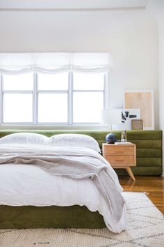 an image of a bed with white sheets and pillows on top of it, in front of a window