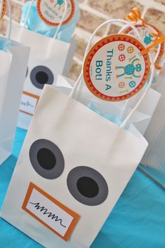 paper bags with faces on them sitting on top of a blue tablecloth covered table