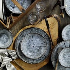 a table topped with plates and knives next to wooden slices