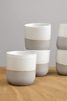 three white and grey cups sitting on top of a wooden table