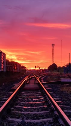 the sun is setting over some railroad tracks