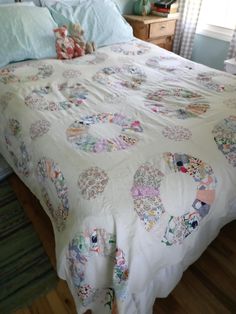 an unmade bed with many hearts on the comforter and pillow cases, along with two nightstands