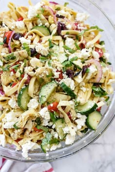 a bowl full of pasta salad with cucumbers and feta cheese