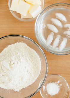 two bowls filled with flour and butter on top of a wooden table next to other ingredients