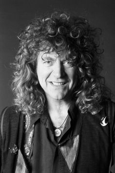 a black and white photo of a woman with curly hair smiling at the camera,