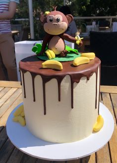 a birthday cake with a monkey on top and bananas in the bottom, sitting on a table