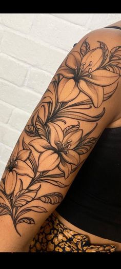 a woman's arm with flowers and leaves tattoo on her left arm, in front of a white brick wall