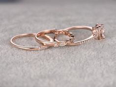 three rose gold wedding rings with diamond accents on a gray surface, close up view