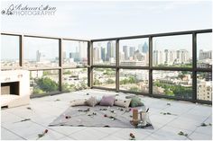 an empty room with large windows overlooking the cityscape and rose petals on the floor