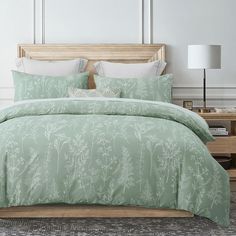 a bed with a green comforter and pillows