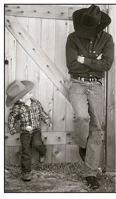 a man standing next to a little boy wearing a cowboy hat