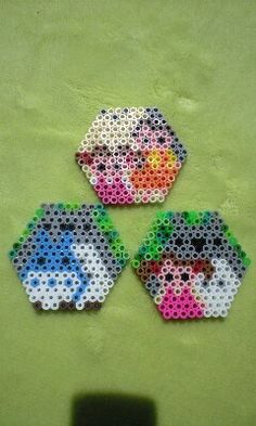 three pieces of perler bead art on a green surface