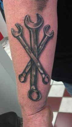 a man's arm with a wrench and spanners tattoo on his forearm