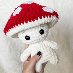 a crocheted mushroom is held up to the camera by someone's hand