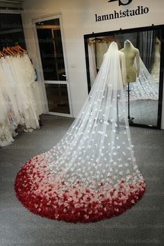 a wedding dress on display in front of a mirror with flowers all over the floor