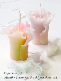 two candles with pink and yellow frosting on them sitting next to each other in front of a white background