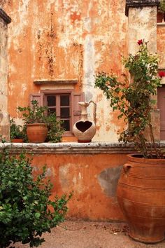 two large vases sitting on top of a stone wall next to plants and flowers