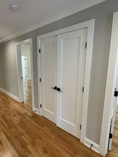 an empty room with white doors and hard wood floors