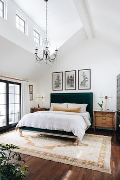 a bed room with a neatly made bed and a chandelier hanging from the ceiling