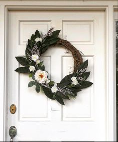 a wreath with white flowers is hanging on the front door