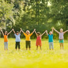 five children standing in a field with their hands up and arms raised to the sky