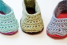 three crocheted slippers sitting on top of a white table next to each other