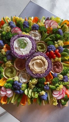 an arrangement of vegetables and dips arranged in the shape of a circle on top of each other