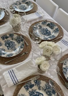 the table is set with blue and white plates, silverware, and napkins