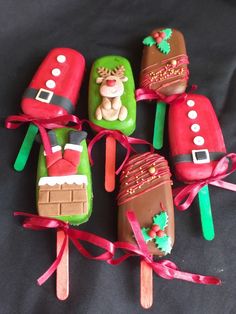 six popsicles decorated like santa claus and reindeers with decorations on them, tied in red ribbon