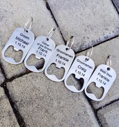 four keychains with names on them are sitting on the ground in front of a brick