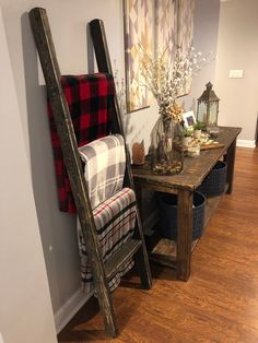 a ladder leaning up against a wall next to a table with a plaid blanket on it