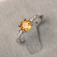 an orange and white diamond ring sitting on top of a gray surface with diamonds around it