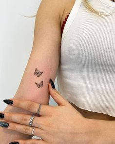 a woman's left arm with two butterflies on her right wrist and the other hand