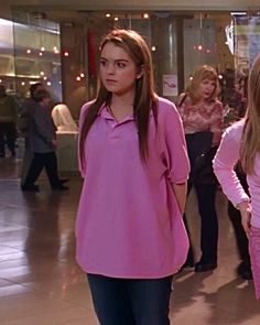 two girls in pink shirts are walking through a mall