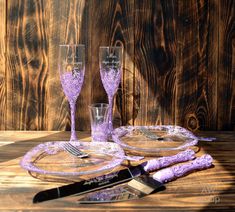 two wine glasses are sitting on a table next to a plate and utensils