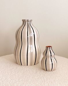 two black and white striped vases sitting on top of a table next to each other