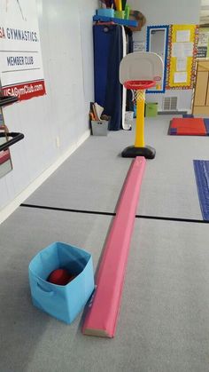 an indoor basketball court in a gym with blue and pink balls on the rims