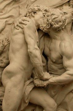 two men touching each other in front of a statue