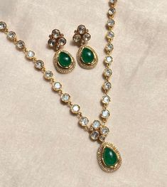 Emerald Kundan Necklace set featuring brilliant green Polki and lustrous Kundan stones, this exquisite necklace is a masterpiece of jewelry craftsmanship. Its timeless design blends traditional charm with contemporary elegance, making it a perfect choice for special occasions. The set includes a matching necklace and earrings, exuding a regal aura that's perfect for weddings, parties, and cultural celebrations. Elevate your style with this stunning Pakistani necklace that captures the essence of Pakistani Necklace, Diamond Pendant Set, Indian Diamond Jewellery, Green Moissanite, Necklace Luxury, Kundan Jewelry, Pearl Jewelry Design, Diamond Pendant Sets, Polki Necklace