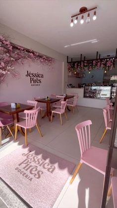 the interior of a restaurant with pink chairs and cherry blossoms on the wall behind it