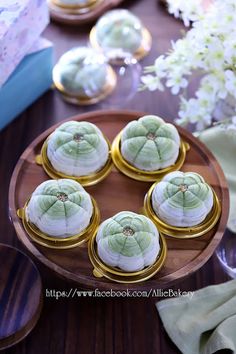 there are many small cakes on the plate with gold trimmings and flowers in the background