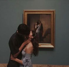 a man and woman kissing in front of a painting