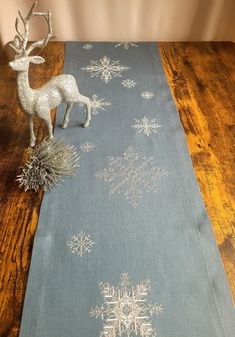 a table runner with snowflakes on it and a silver reindeer figurine