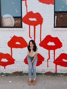 a woman standing in front of a wall with red lipstick painted on it