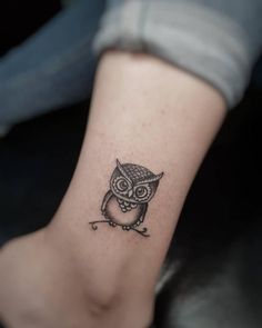 an owl tattoo on the ankle is shown in black and grey colors, with small details