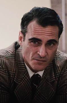 a man in a suit and tie looking at the camera with an intense look on his face