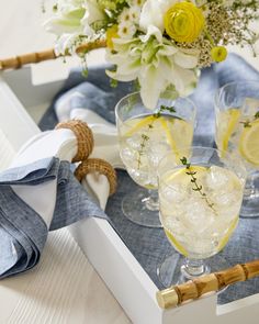 two glasses filled with lemonade sitting on top of a table next to napkins and flowers